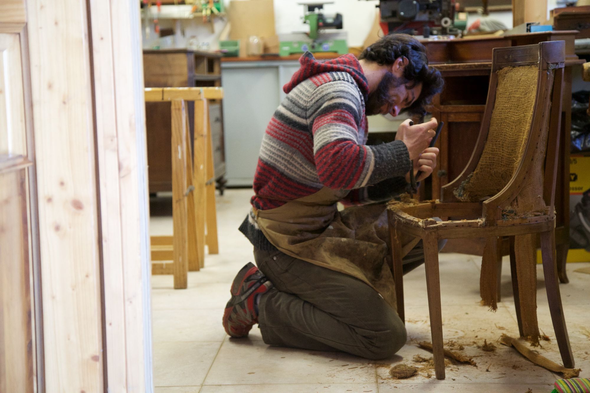 A craftsman restoring a wooden chair in the workshop